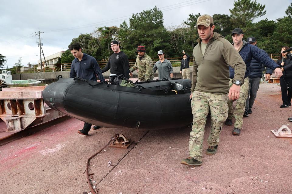 US military personnel carry a dinghy as they head out to search for the crash of a US CV-22B Osprey aircraft, on the island of Yakushima, Kagoshima Prefecture on December 1, 2023 (JIJI Press/AFP via Getty Images)