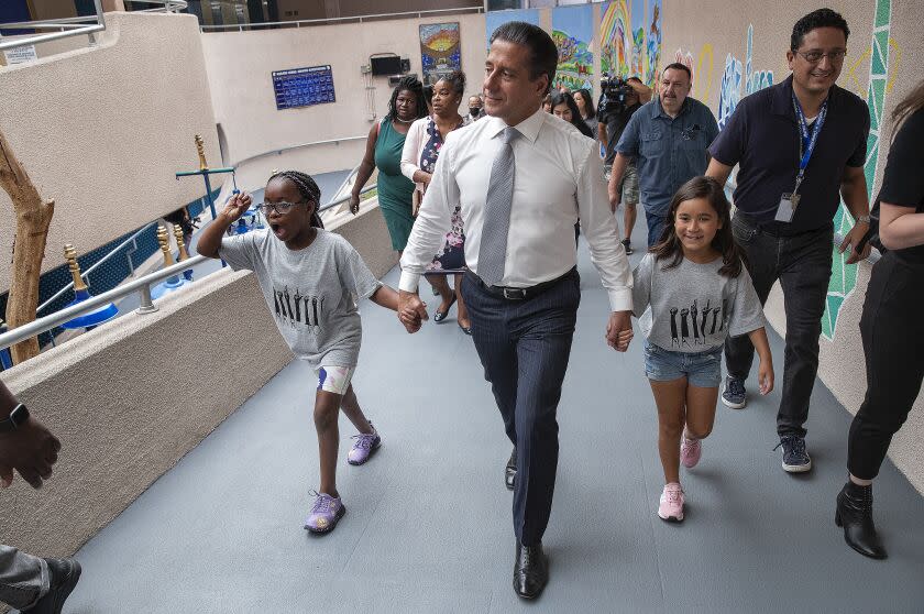 LOS ANGELES, CA-AUGUST 15, 2022: Seven Chandler, 9,left, a 4th grader at Marlton School in Los Angeles, and Kristalyn Barrera, 8, a 2nd grader, serve as ambassadors while leading Los Angeles Unified Superintendent Alberto Carvalho to a classroom during a visit to the school on the first day of class. (Mel Melcon/Los Angeles Times)