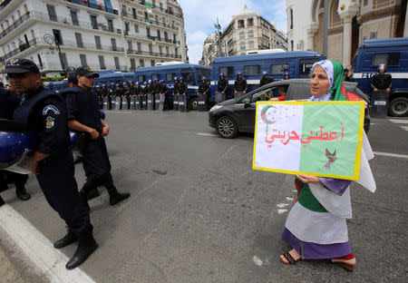 A demonstrator carries a banner as she walks past police officers standing guard during an anti-government protest in Algiers, Algeria May 24, 2019. The banner reads: "Give me my freedom". REUTERS/Ramzi Boudina