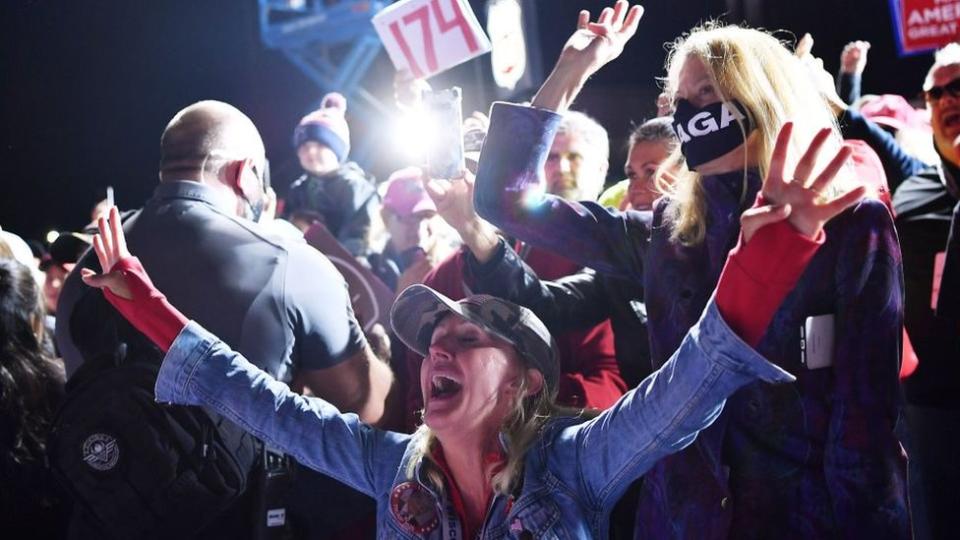 Una mujer con los brazos abiertos en celebración en acto de campaña de Trump en Mosinee.