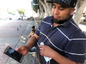 José Edgar Zuleta shows a photo in Tijuana, Mexico, of his 21-year-old on Oct. 9, 2020. Zuleta, whose business selling religious jewelry in the Mexican city of Puebla dried up when the pandemic hit, climbed Trump's 30-foot (9-meter) wall with a special ladder. He moved through brush in a heavily patrolled area for about a half-hour with two women before getting caught. His son, who cleared the wall ahead of him, got picked up hours later. (AP Photo/Elliot Spagat)