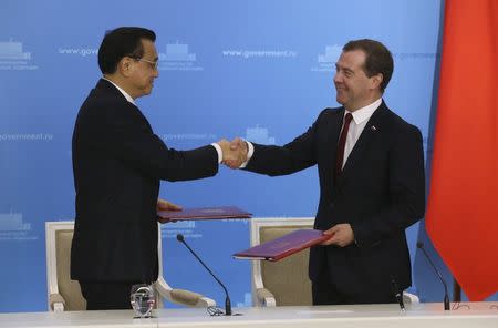 Russia's Prime Minister Dmitry Medvedev (R) shakes hands with China's Premier Li Keqiang during a signing ceremony in Moscow, October 13, 2014. REUTERS/Yekaterina Shtukina/RIA Novosti/Pool