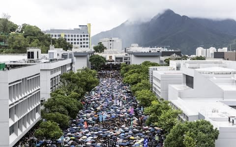 Students gather under umbrellas on the University Mall at the Chinese University of Hong Kong (CUHK) during a class boycott rally in Hong Kong - Credit: Bloomberg