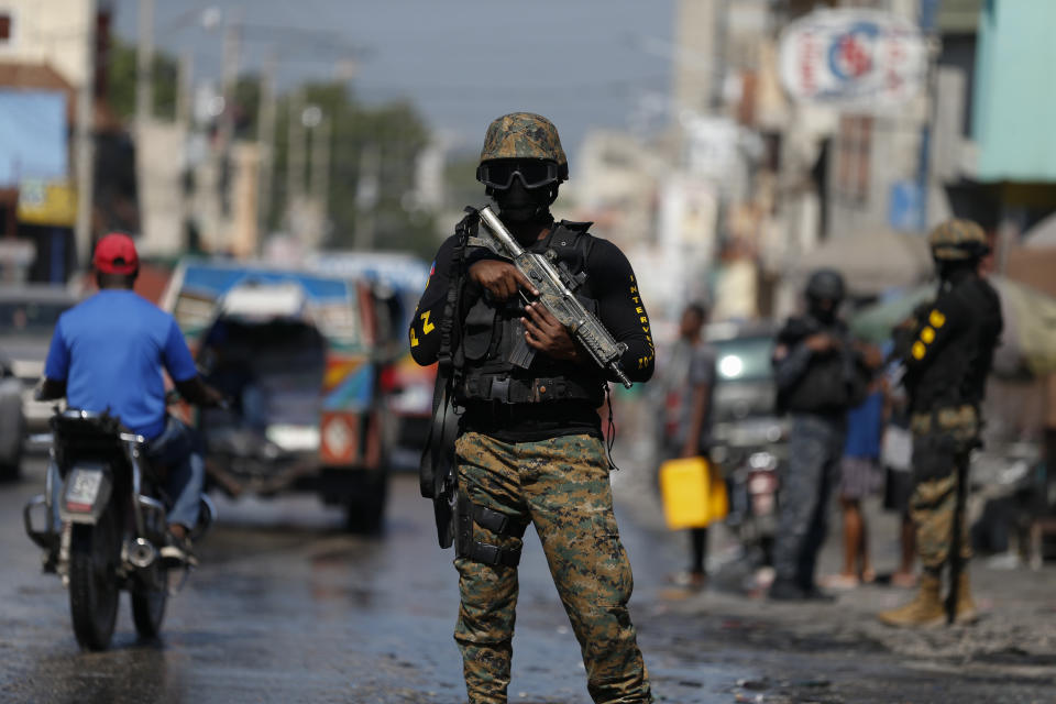 Members of the presidential guard provide security on the road as they await the passage of the president's convoy on its way to the National Palace, in Port-au-Prince, Haiti, Tuesday, Oct. 15, 2019. Haiti's embattled President Jovenel Moïse faced a fifth week of protests as road blocks and marches continue across the country, after opposition leaders said they will not back down on their call for Moïse to resign.(AP Photo/Rebecca Blackwell)