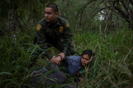 FILE PHOTO: U.S. Border Patrol agent Marcelino Medina looks for others as he apprehends a migrant woman and man for illegally crossing into the U.S. border from Mexico near McAllen, Texas May 2, 2018. REUTERS/Adrees Latif/File Photo