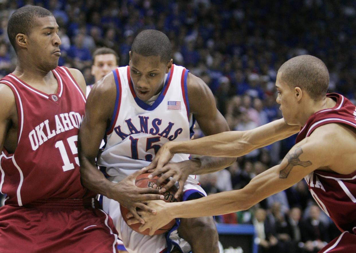 Kansas guard Mario Chalmers (15) is tied up by Oklahoma guard Austin Johnson, right, and David Godbold (15) during the first half of their college basketball game at Allen Fieldhouse in Lawrence, Kan., Sunday, Feb. 5, 2006. (AP Photo/Orlin Wagner)