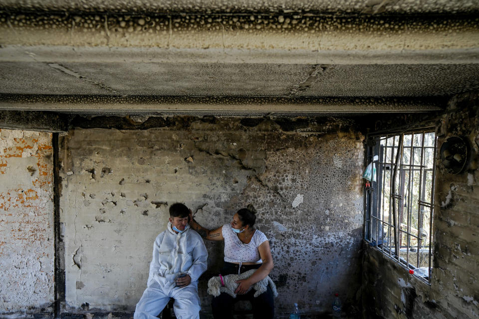 Camila Lange, who is 7-months-pregnant, and her husband Felipe Corvalan sit with their dog Florencia inside their home that was burned by a deadly forest fire in Vina del Mar, Chile, Monday, Feb. 5, 2024. (AP Photo/Esteban Felix)