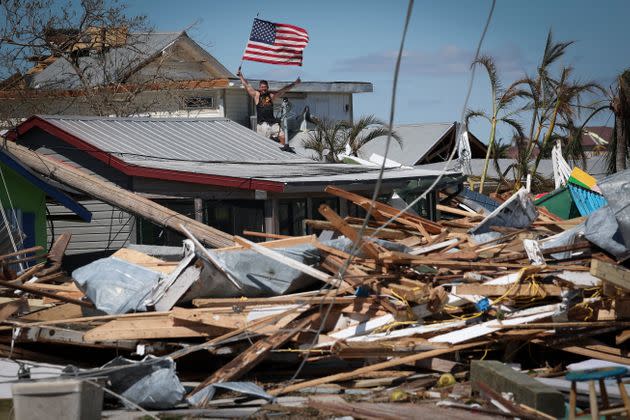 Whitney Hall waves to a friend from the remains of his home while waving the American flag amidst wreckage left in the wake of Hurricane Ian on the island of Matlacha on Sept. 30. (Photo: Win McNamee via Getty Images)