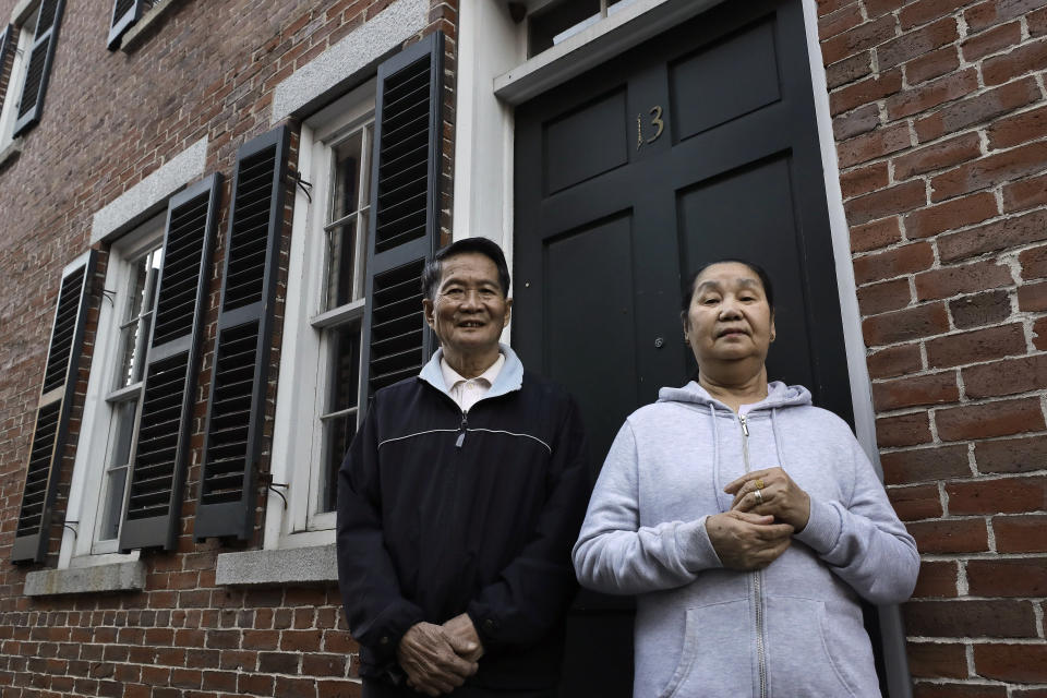 In this Wednesday, May 20, 2020 photo Pay Reh, left, and Poe Meh, right, originally of Burma, also known as Myanmar, stand for a photograph at the entrance to their home, in Lowell, Mass. The elderly couple, who came to Massachusetts as refugees in 2011, were granted a special naturalization oath ceremony in May of 2020 after their lawyer argued that they faced financial hardship if they weren't naturalized immediately. (AP Photo/Steven Senne)