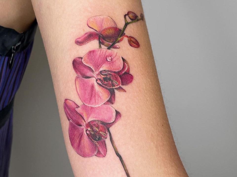 Pink, colored tattoo of an orchid on arm