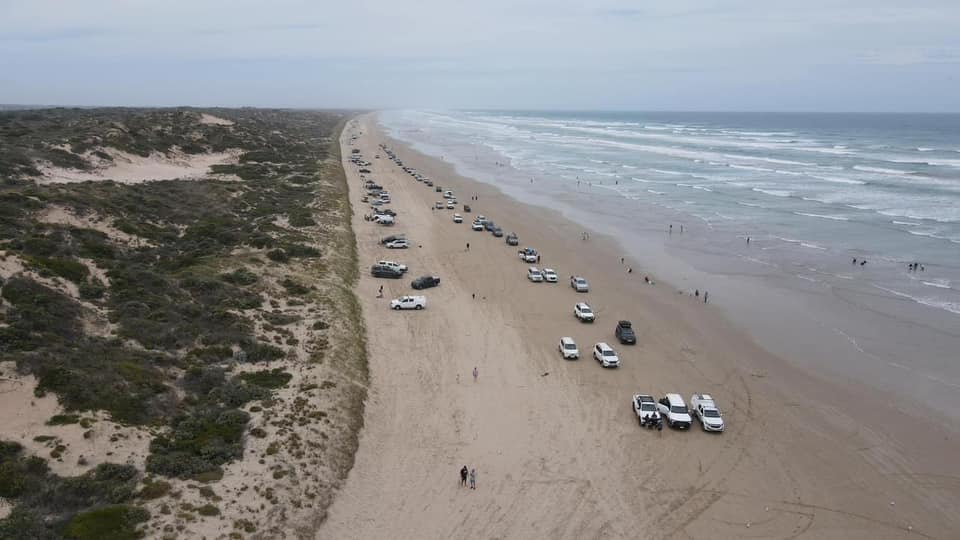 Aerial image of a line of cars on the sand at Goolwa beach. 