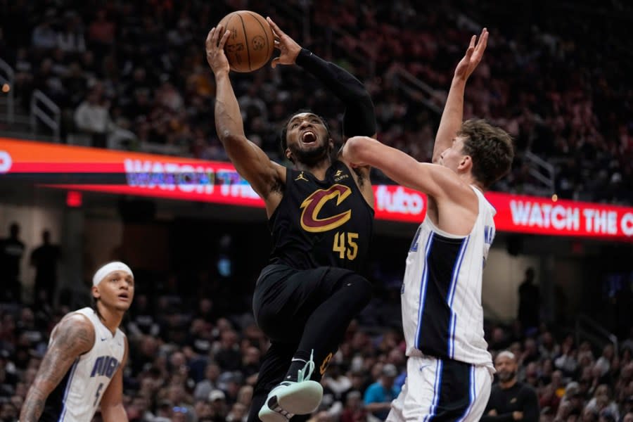 Cleveland Cavaliers guard Donovan Mitchell (45) shoots between Orlando Magic forward <a class="link " href="https://sports.yahoo.com/nba/players/6691/" data-i13n="sec:content-canvas;subsec:anchor_text;elm:context_link" data-ylk="slk:Paolo Banchero;sec:content-canvas;subsec:anchor_text;elm:context_link;itc:0">Paolo Banchero</a> (5) and forward <a class="link " href="https://sports.yahoo.com/nba/players/6550/" data-i13n="sec:content-canvas;subsec:anchor_text;elm:context_link" data-ylk="slk:Franz Wagner;sec:content-canvas;subsec:anchor_text;elm:context_link;itc:0">Franz Wagner</a>, right, in the first half of Game 7 of an NBA basketball first-round playoff series Sunday, May 5, 2024, in Cleveland. (AP Photo/Sue Ogrocki)