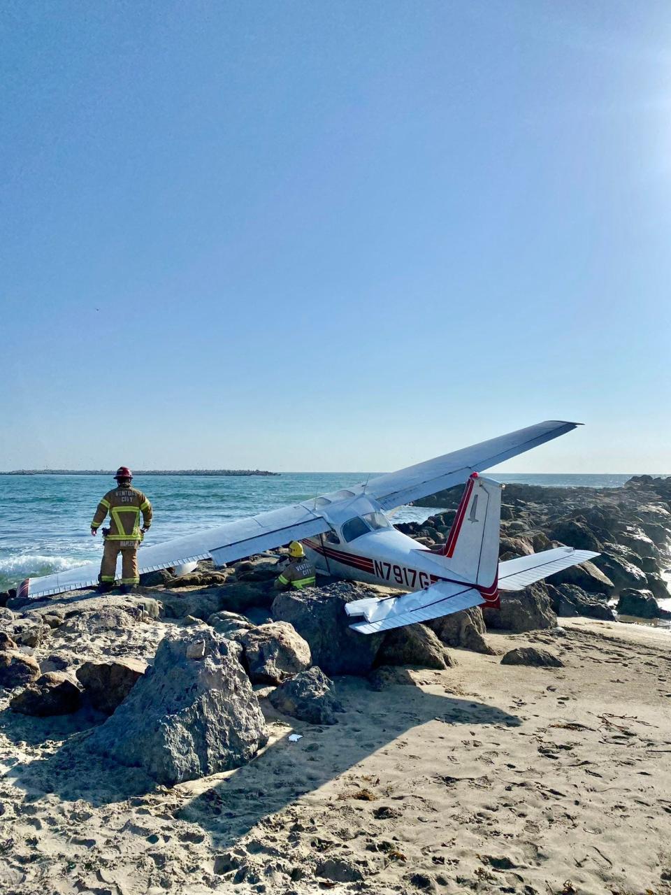 Firefighters check the scene after a single-engine Cessna landed on a rocky jetty at Ventura's Marina Beach Friday afternoon.
