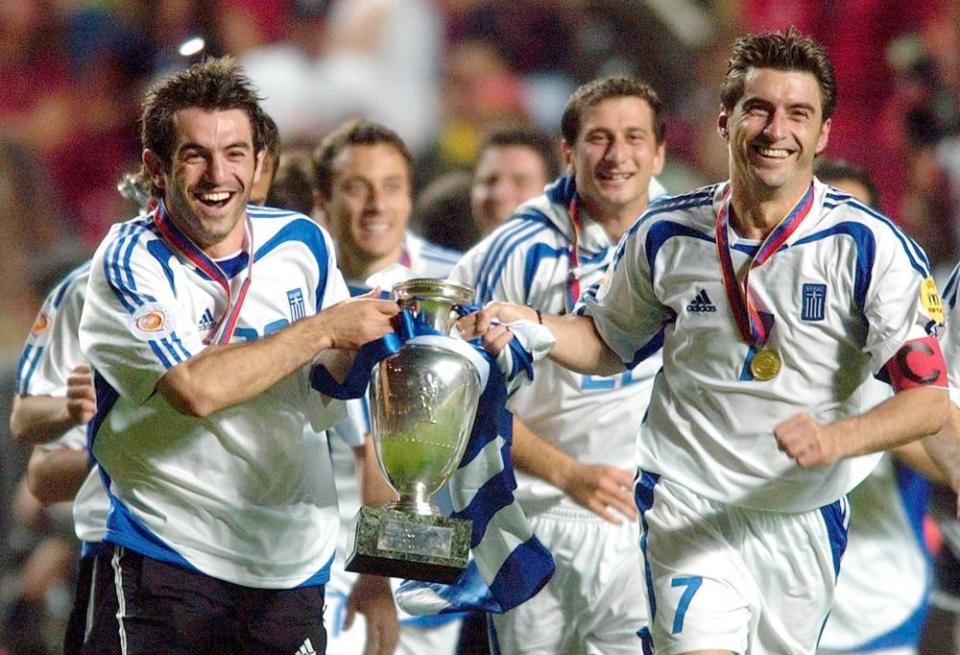 Georgios Karagounis, left, and Theodoros Zagorakis of Greece run with the trophy after their team’s 1-0 victory over Portugal in the Euro 2004 soccer championship final.