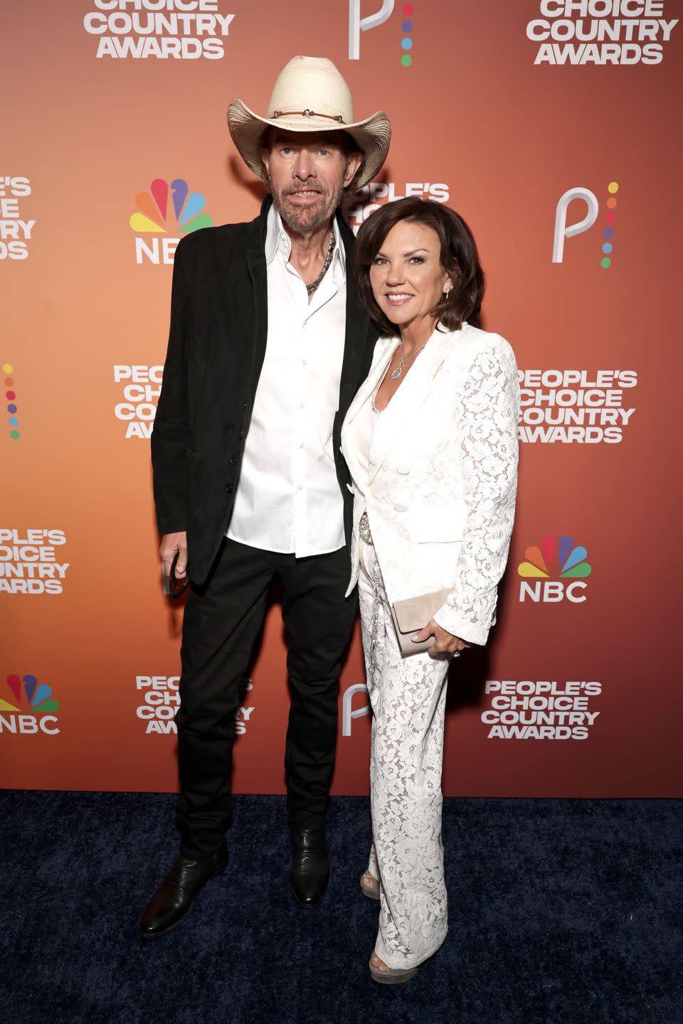 toby keith wearing a cowboy hat and posing for a photo with tricia lucus who wears all white