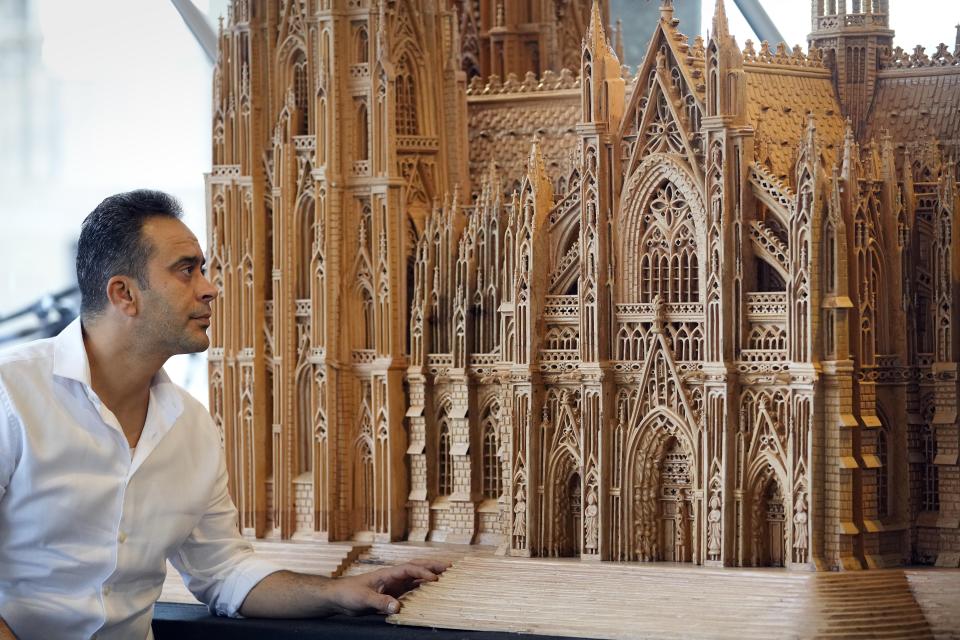 Fadel Alkhudr from Syria poses near the south part of his wooden model of the word heritage Cologne Cathedral on display at the Domforum in Cologne, Germany, Monday, June 20, 2022. Fadel Alkhudr, 42, a woodcarver and artist orginally from Aleppo, Syria, fled the war in his home country and arrived in the western german city of Cologne in 2015. In 2019 he started to carve the local Cologne Cathedral in his small basement - without any plans or drawings, using only cell phone photos of the cathedral as a template. (AP Photo/Martin Meissner)