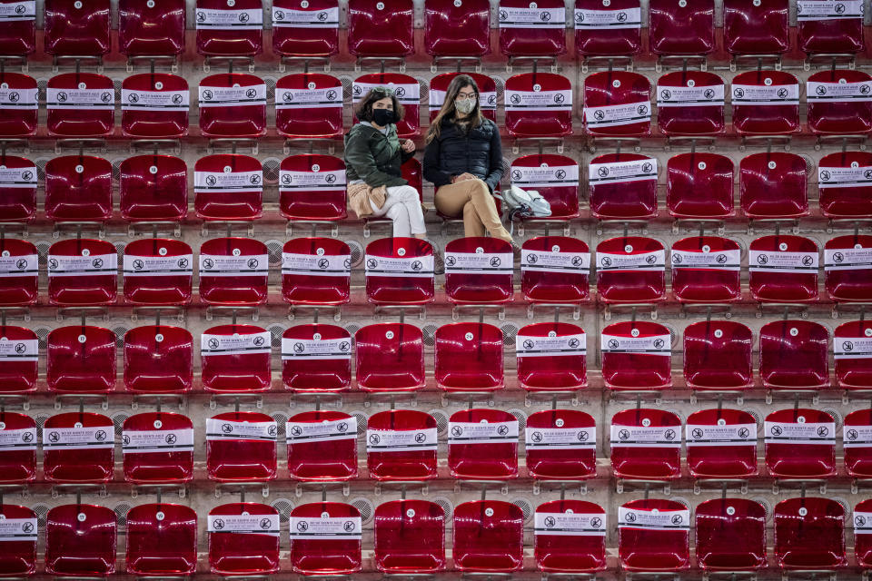 Spectators follow the match between United States' Shelby Rogers and Ashleigh Barty during the Mutua Madrid Open tennis tournament in Madrid, Spain, Thursday, April 29, 2021. The white banners covering the seats read "Do not sit here. Keep social distance". (AP Photo/Bernat Armangue)