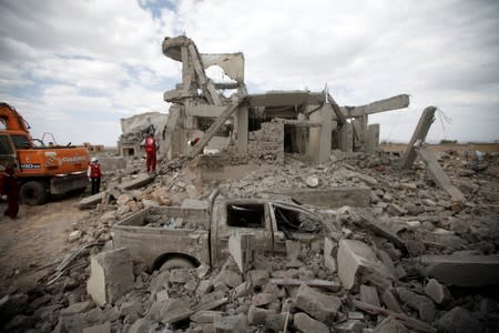 Destroyed car is seen between rubble as Red Crescent medics inspect the site of Saudi-led air strikes on a Houthi detention centre in Dhamar