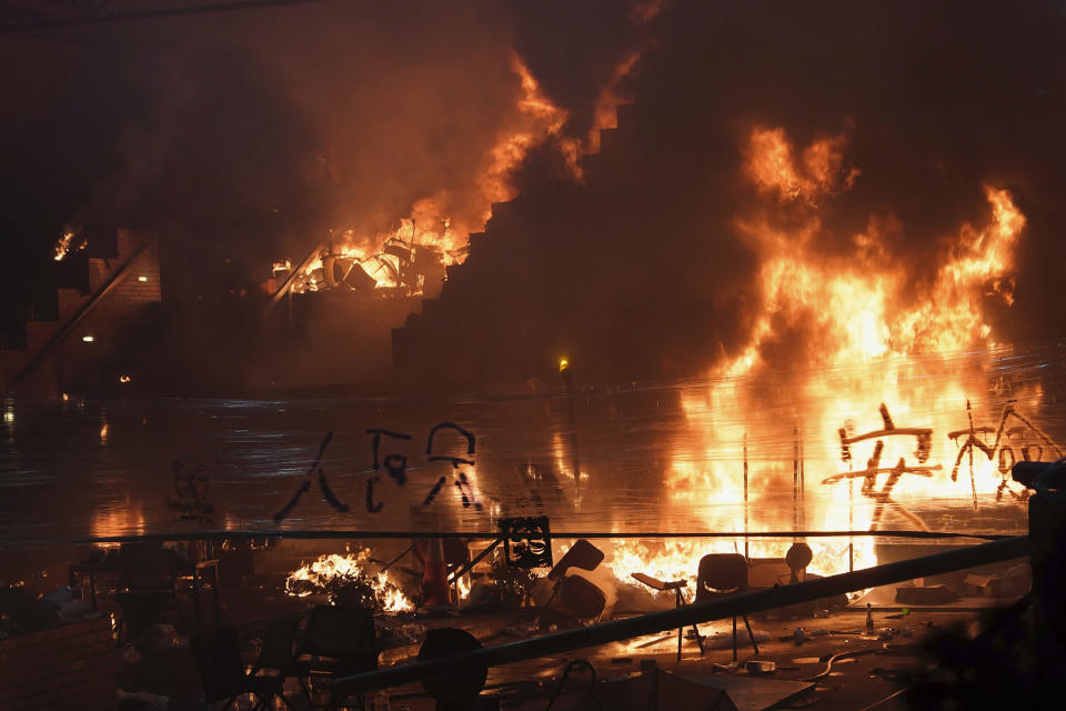 Fires burn at the steps to Hong Kong Polytechnic University as police storm the campus in Hong Kong, early Monday, Nov. 18, 2019. Hong Kong police have stormed into a university campus held by protesters after an all-night standoff. Fiery explosions could be seen inside as riot officers entered before dawn Monday. (AP Photo/Vincent Yu)