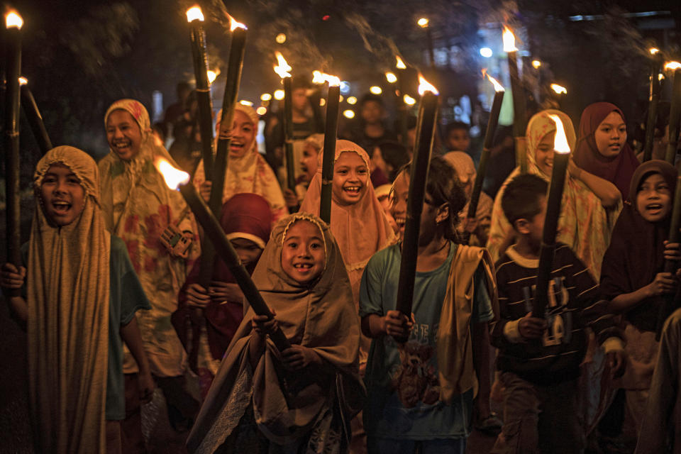 FILE - Muslim girls carry torches during a parade to celebrate the eve of Eid al-Fitr, the holiday marking the end of the holy fasting month of Ramadan, in Polewali Mandar, West Sulawesi, Indonesia, Friday, April 21, 2023. (AP Photo/Yusuf Wahil, File)