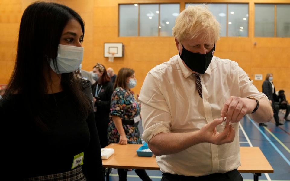 Boris Johnson shakes a dose of the Pfizer vaccine before being administered as he visits a vaccination centre in London - Matt Dunham/AP