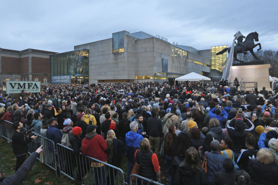 Spectators watch during the unveiling ceremony for a statue titled Rumor's of War by artist Kehinde Wiley at the Virginia Museum of Fine arts in Richmond, Va., Tuesday, Dec. 10, 2019. The tarp covering the statue got stuck on the statue during the ceremony. (AP Photo/Steve Helber)