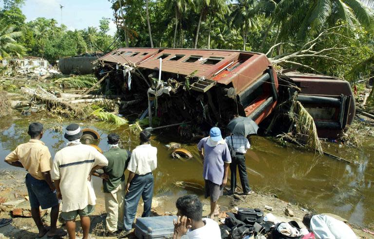 Sri Lankan villagers look at the derailed Ocean Queen Express in Sinigame, near the town of Hikaduwa on the southwestern coast of Sri Lanka three days after the train was swept away by the tsunami