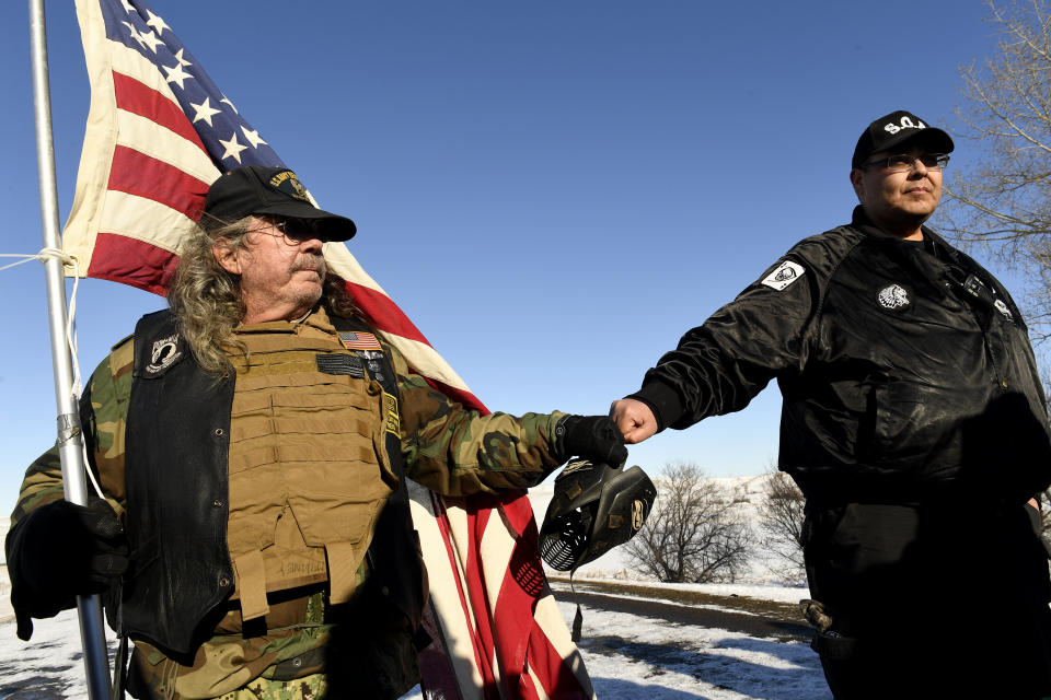 US Navy veteran Bob McHaney, left, and Bill Runningfisher, of the Gros Ventre nation, right, press their fists together in solidarity while on a bridge near Oceti Sakowin Camp on the edge of the Standing Rock Sioux Reservation.