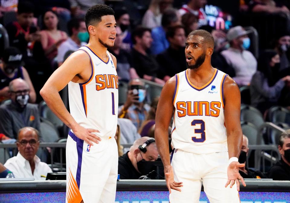 Nov 2, 2021; Phoenix, Arizona, USA; Phoenix Suns guard Devin Booker (1) and guard Chris Paul (3) talk during a time out against the New Orleans Pelicans at Footprint Center.