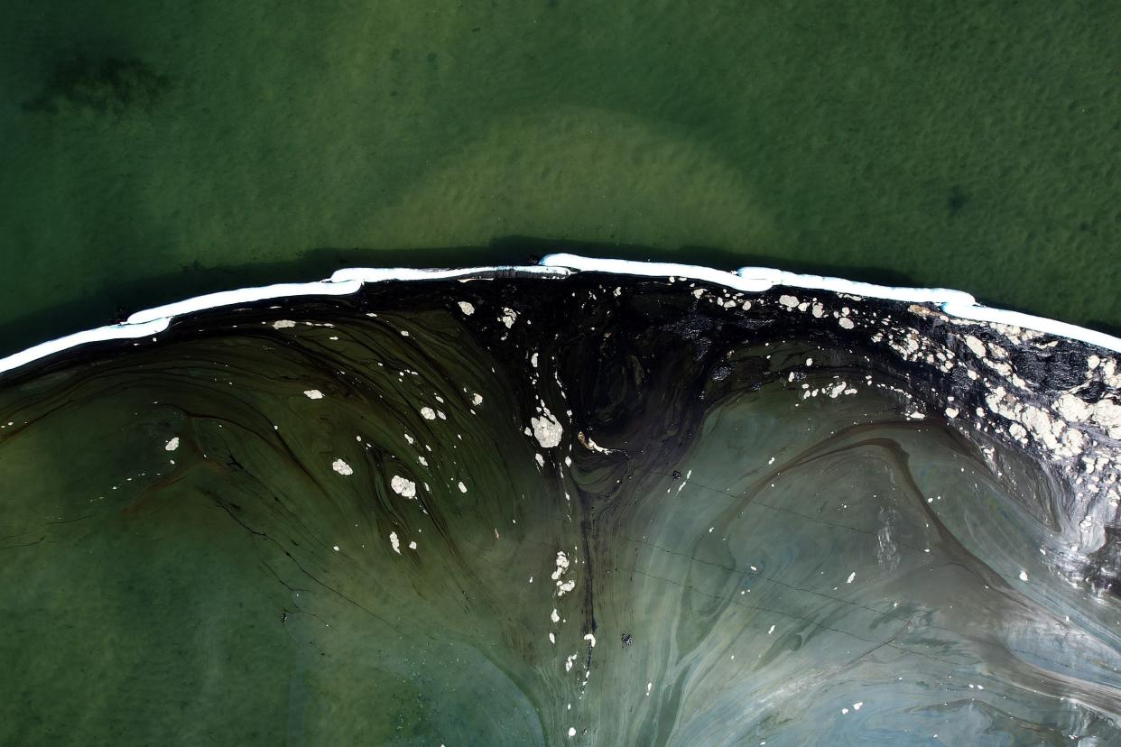 An aerial photo shows floating barriers known as booms set up to try to stop further incursion into the Wetlands Talbert Marsh after an oil spill in Huntington Beach, Calif. on Monday, Oct. 4, 2021.