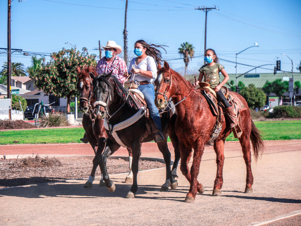 A father and his two daughters ride into a cabalgata on March 28, 2021. (Connecting Compton)