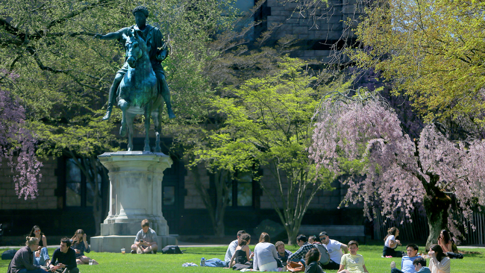 People relax on a lawn on the campus of Brown University in Providence, RI on April 25, 2019.