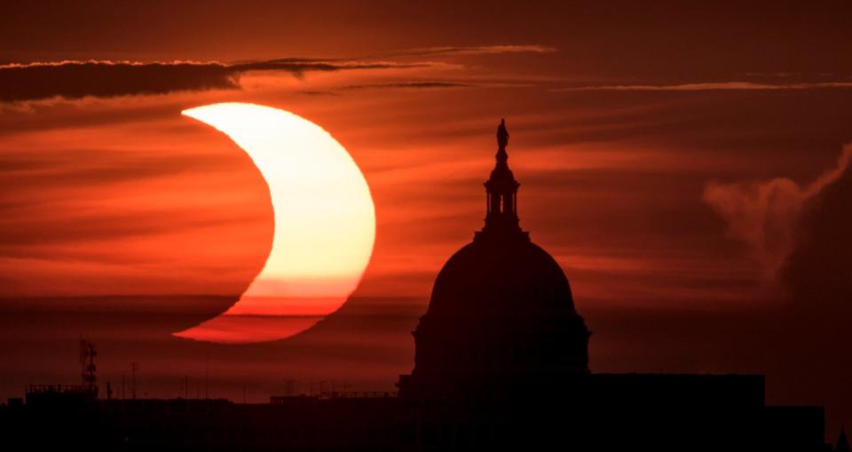 The partial solar eclipse is seen as the sun rises to the left of the United States Capitol building (NASA via Getty Images)