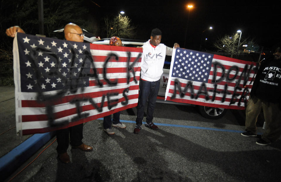 Activists protesting the police shooting of a black man in an Alabama shopping mall hold U.S. flags painted with the words "Black lives don't matter" in Hoover, Ala., Tuesday, Feb. 5, 2019. Demonstrators are upset with the state's decision against prosecuting a police officer who shot and killed Emantic "EJ" Bradford Jr. in a shopping mall on Thanksgiving night. (AP Photo/Jay Reeves)