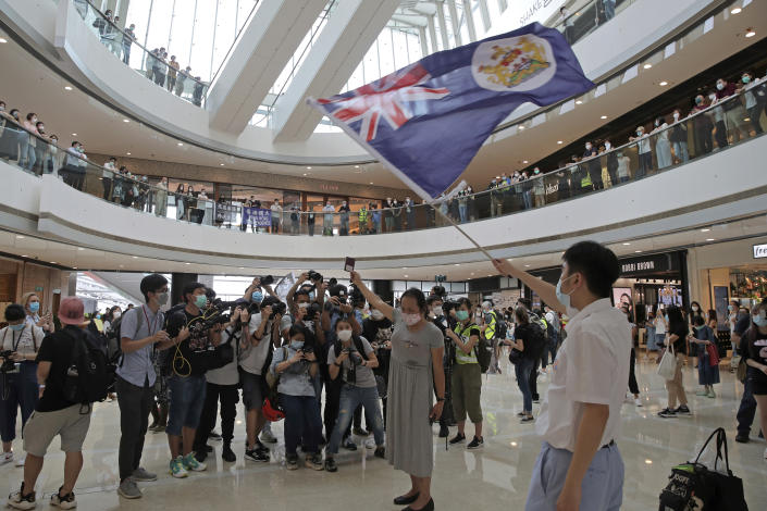 Protesters hold a British National (Overseas) passport and Hong Kong colonial flag in a shopping mall during a protest against China's national security legislation for the city, in Hong Kong, Friday, May 29, 2020. The British government says t it will grant hundreds of thousands of Hong Kong residents greater visa rights if China doesn't scrap a planned new security law for the semi-autonomous territory. U.K. Foreign Secretary Dominic Raab said about 300,000 people in Hong Kong who hold British National (Overseas) passports will be able to stay in Britain for 12 months rather than the current six. (AP Photo/Kin Cheung)