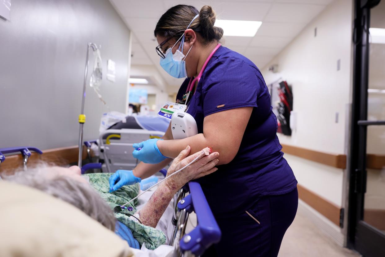 A registered nurse cares for a patient on a stretcher in a hallway of the overloaded Emergency Room at Providence St. Mary Medical Center amid a surge in COVID-19 patients in Southern California on January 5, 2021 in Apple Valley, California.