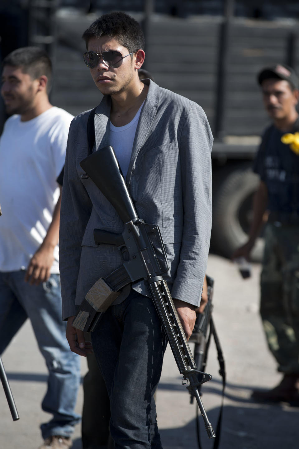 An armed man belonging to the Self-Defense Council of Michoacan, (CAM), stands guard at a checkpoint in Antunez, Mexico, Tuesday, Jan. 14, 2014. The Mexican government moved in to quell violence between vigilantes and a drug cartel, and witnesses say several unarmed civilians were killed in an early Tuesday confrontation. (AP Photo/Eduardo Verdugo)