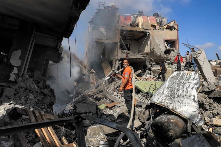 Un miembro de la defensa civil palestina rocía un edificio con una manguera para apagar un incendio en un edificio derrumbado después del bombardeo israelí en Khan Yunis, en el sur de la Franja de Gaza, el 8 de noviembre de 2023