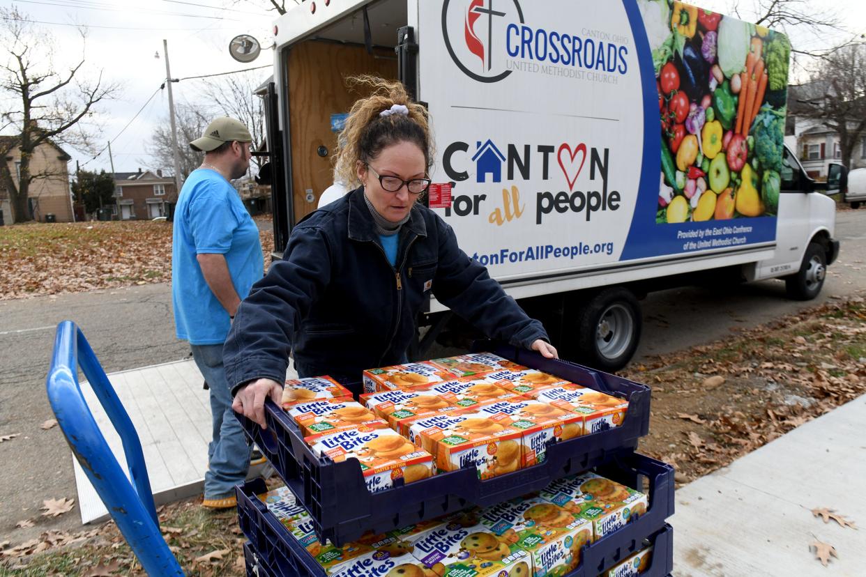 Volunteer Lilly Brunoni carries in food for the new Shorb Neighborhood Market and Connection Center that opened at 603 Shorb Ave. NW in Canton on Nov. 28.