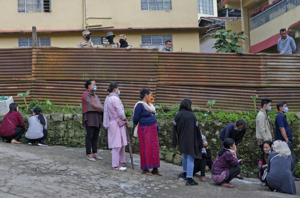 Nagas wearing face masks as a preventive measure against the coronavirus wait to cast their votes outside a polling booth during by-elections in Kohima, capital of the northeastern Indian state of Nagaland, Tuesday, Nov. 3, 2020. Elections are being held in two constituencies in the state after the seats fell vacant following the demise of their respective lawmakers. (AP Photo/Yirmiyan Arthur)