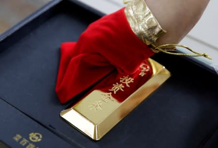 A sales assistant displays a 1000 gram gold bar to be sold as an investment purchase at Caibai Jewelry store, in Beijing, China