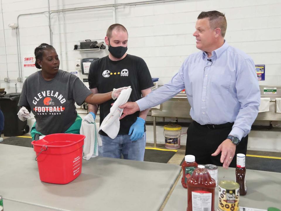 Sarah Conwell, left, and her coworker Eric Gorring put their boss, Erich Weiss, the owner of Cuyahoga Falls Chick-Fil-A to work as they volunteer Monday at the Akron-Canton Regional Foodbank. Weiss is paying employees their normal wages while his store is closed for renovations for three months. In return, he's asking them to volunteer at a few non profits.