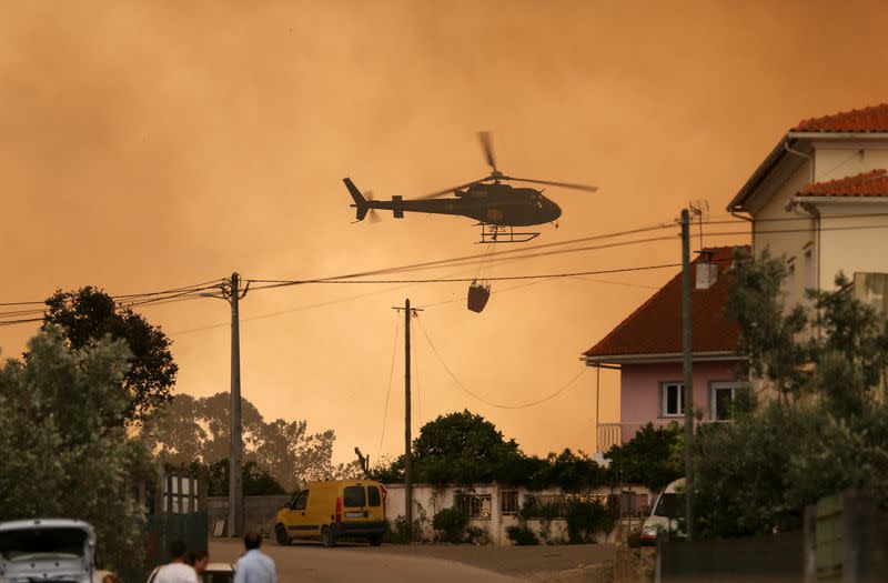 Un helicóptero de extinción de incendios trabaja para contener un incendio forestal en Leiria, Portugal,