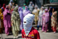 <p>A Kashmiri Muslim masked protester stands in front the women protesters shouting anti Indian and pro Kashmir Independence slogans during a protest, following weeks of violence that has left over 50 people dead and thousands injured, on July 28, 2016 in Srinagar, the summer capital of Indian administered Kashmir, India. (Photo: Yawar Nazir/Getty Images)</p>