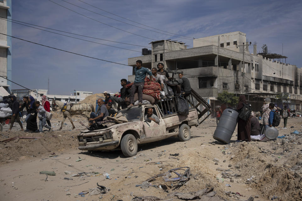 Palestinians drive and walk through the destruction in the wake of an Israeli air and ground offensive in Khan Younis, southern Gaza Strip, Monday, April 8, 2024. Israel says it has withdrawn its last ground troops from the city, ending a four-month operation. (AP Photo/Fatima Shbair)