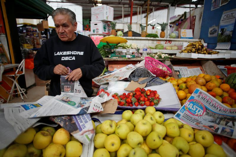 A man makes paper cones to deliver fruit to his customers, instead of plastic bags, at his stall at a market in Mexico City