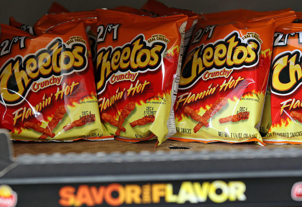Bags of flamin' hot cheetos on a shelf.