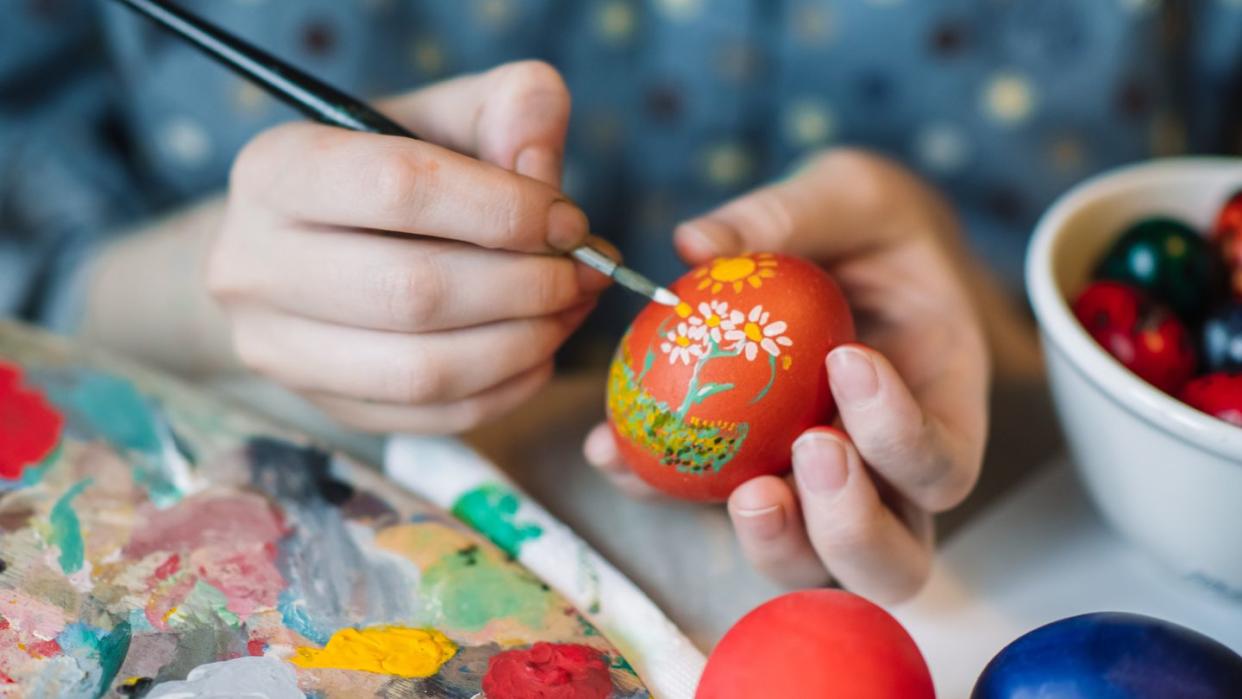 young girl painting on easter egg