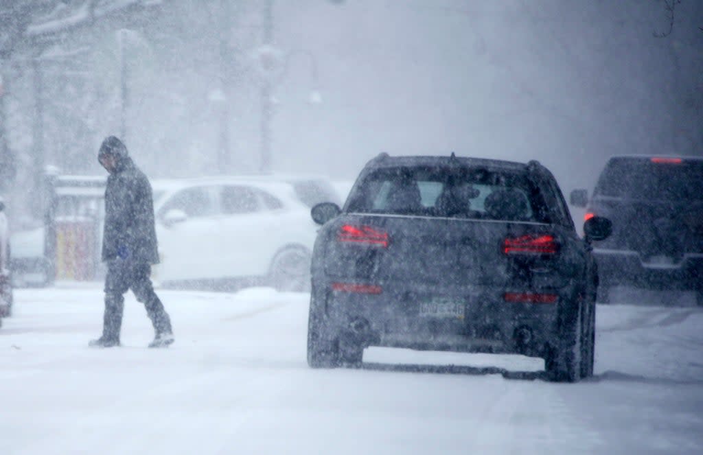 A pedestrian crosses the street as a winter storm drops several inches of snow on Tuesday in Denver. A bomb cyclone is forecast to bring similar conditions to the East Coast this weekend (AP)