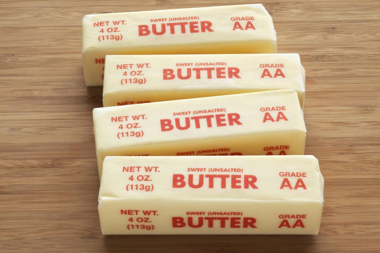 Four quarter pound sticks of sweet unsalted AA grade butter on a bamboo cutting board.